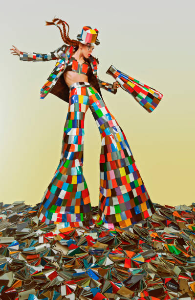 maestro di circo femminile vestito con un abito colorato e con in mano un megafono, in piedi nel mezzo di un mucchio di campioni di colore - art coat full length foto e immagini stock