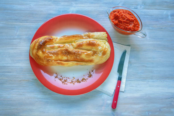 Balkan cuisine. Burek ( byrek, borek, bourekas, boreg ) is a baked filled pastries, popular national dish. Ajvar, salad from bell peppers.  Rustic background,  copy space