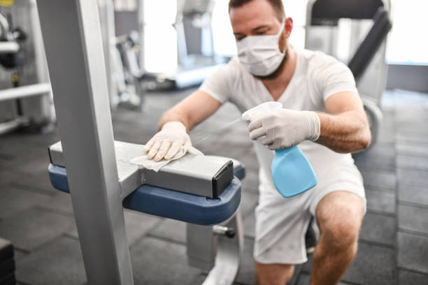 istock Worker In Bodybuilding Center Cleaning Equipment While Wearing Face Mask 1339127793