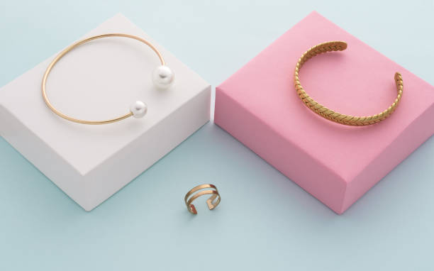 istock Modern golden bracelets on pink and white boxes and double shape ring on blue background 1339130650
