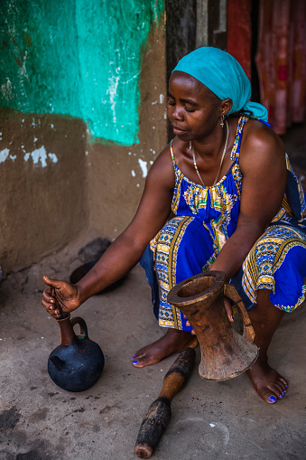 Ethiopian woman during coffee ceremony - putting coffee grounds  into a special vessel which contain boiled water, northern Ethiopia, Africa. A coffee ceremony is a ritualised form of preparing and later drinking coffee.