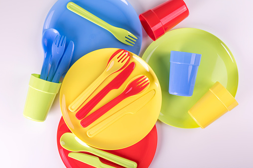 Bright colorful plastic disposable tableware isolated on white background. Flat lay.