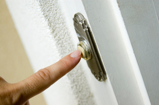 A finger ringing a doorbell.