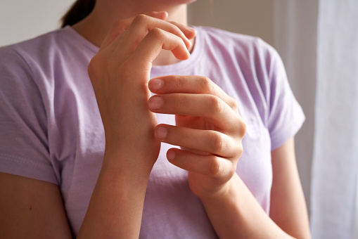 Teenage girl practicing EFT or emotional freedom technique - tapping on the karate chop point, closeup