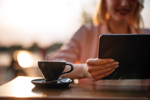 Unrecognizable Woman Using Digital Tablet While Drinking Coffee in a Cafe
