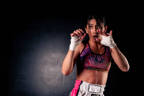 istock Beautiful woman practicing and training martial arts or kick-boxing waiting in counter-attack position. Isolated on black background. 1339144466