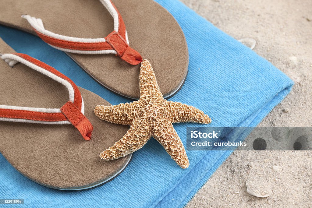 Beachwear in the Sand A beach towel, flip flops and starfish in the sand. Beach Stock Photo