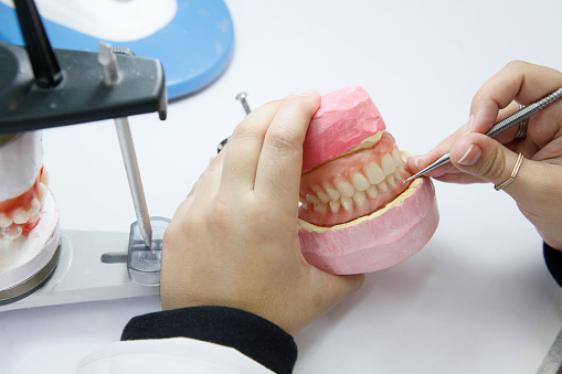 Dental technician dentist man working with dentures in a laboratory on a jaw model. Selective focus