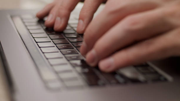 Close up macro of hands typing on laptop keyboard mac computer