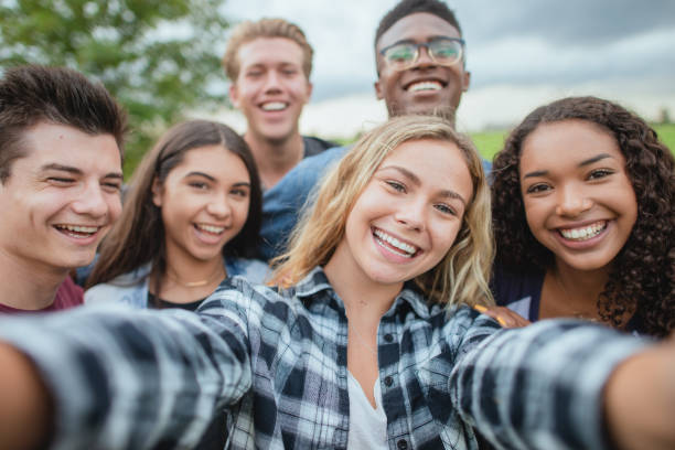 Multiracial group of teenagers taking a selfie A multi ethnic group of teenagers huddled together for a selfie while standing outside. They are dressed casually. They are happy and smiling. selfie girl stock pictures, royalty-free photos & images