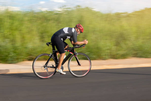 Cyclists in colorful outfits riding fast through city during large urban bike event with artistic motion blur. Vertical sport background. Concept of motion, sport and community