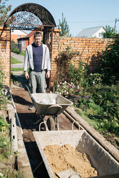istock A man unloads sand into a cement mixture for pouring a garden path 1339167229