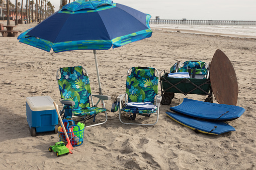 Beach equipment in green and blue with no people. All set up in the summer at the beach.