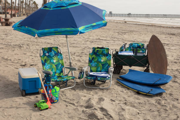 Fun at the beach with ice chest, umbrella, chairs, toys, boogie boards, wagon, beach towels, and skimboard stock photo