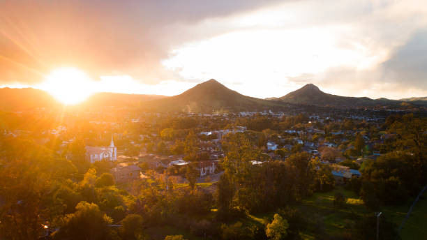 Beatific golden sunlight flooding over mountain range onto small town with white church with steeple stock photo