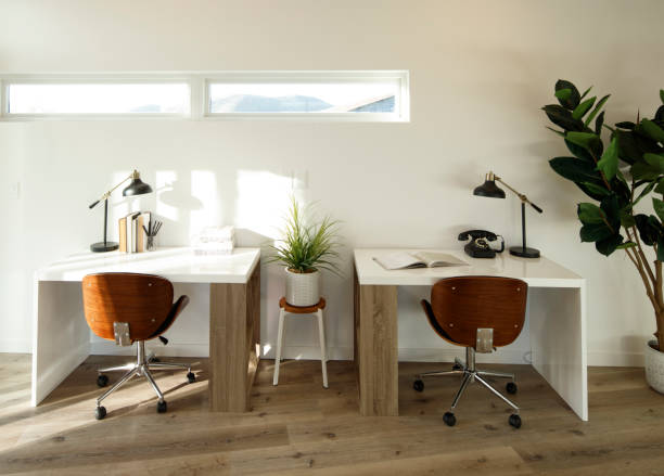 Small contemporary office with two small desks, rolling chairs, and lots of light stock photo
