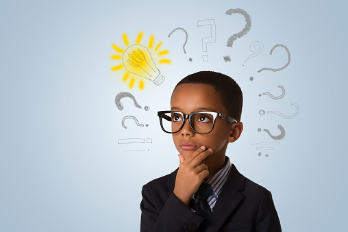 Adorable african little boy wearing glasses and thinking with many question marks and lightbulb. Concept of ideas