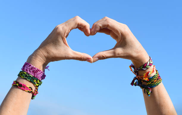 Hands making heart symbol on sky background. friendship bracelets on wrists Hands making heart symbol on sky background. friendship bracelets on wrists friendship bracelets hands stock pictures, royalty-free photos & images