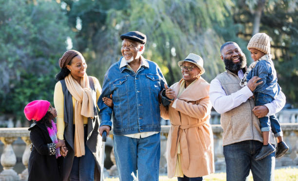 familia afroamericana de tres generaciones caminando en el parque - coat grandfather grandchild granddaughter fotografías e imágenes de stock