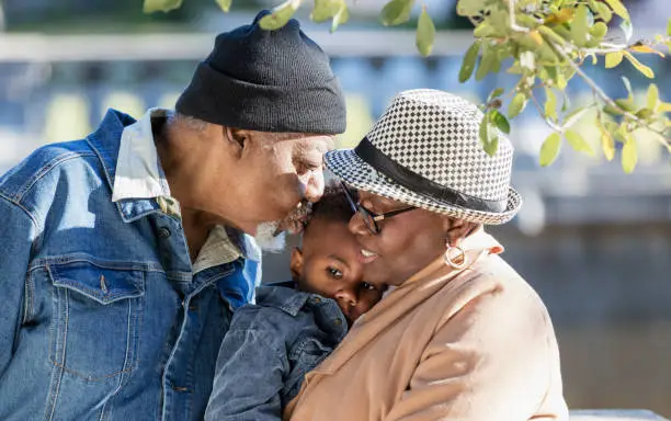 Photo of African-American grandparents, kissing grandson