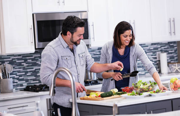 istock Multiracial couple in kitchen making salad, conversing 1339171714