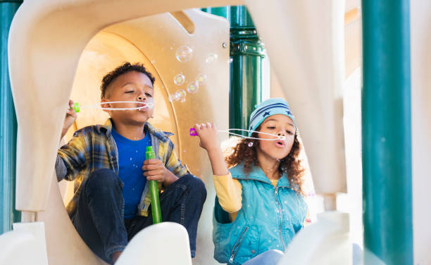 istock Multiracial siblings on playground blowing bubbles 1339173278