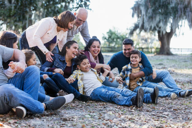 wielopokoleniowa latynoska rodzina w parku, usiądź na ziemi - uncle zdjęcia i obrazy z banku zdjęć
