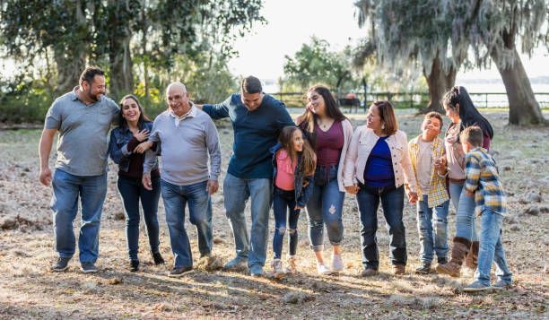 famiglia ispanica multi-generazione che cammina nel parco fianco a fianco - riunione di famiglia foto e immagini stock
