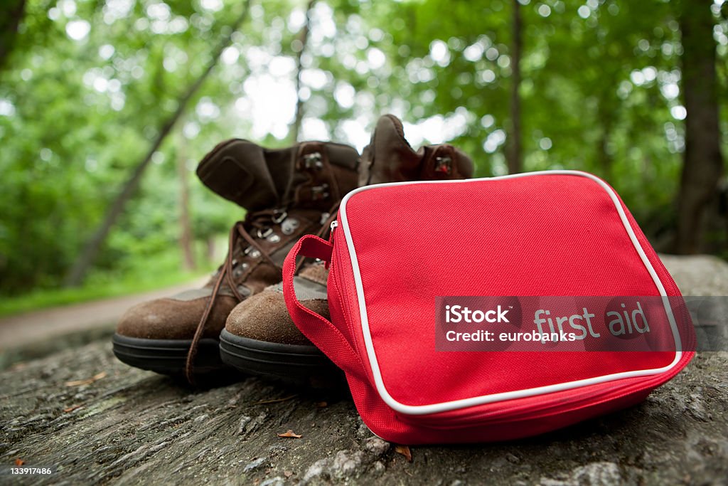 First Aid Kit on Hike A red first aid kit with hiking boots in the woods. First Aid Kit Stock Photo