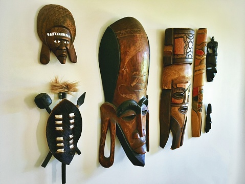 Close-up of a Boho Style Collection of African Wooden Mask Souvenirs picked up whilst travelling displayed on wall. I own these masks and collected them whilst on my travels, I also displayed them on my walls.
