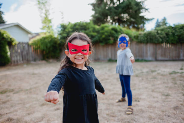 Lifestyle photos of two hispanic little girls ages 5 and 4 in super hero mask playing together. They're off on an adventure to save the world.