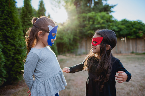 Lifestyle photos of two hispanic little girls ages 5 and 4 in super hero mask playing together. They're off on an adventure to save the world.