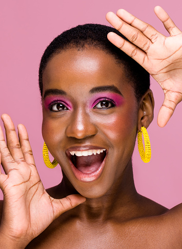 Excited young African woman with mouth open frames face with hands