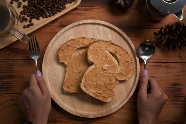 Female holding spoon and fork ready to eat toast bread with peanut butter.