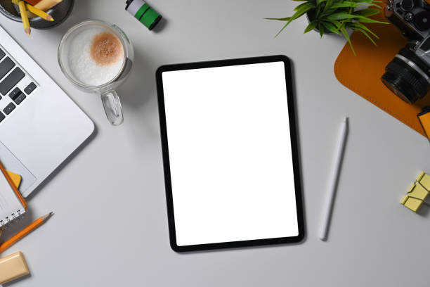 istock Above view digital tablet with empty display, stylus pen and camera on white desk. 1339188548