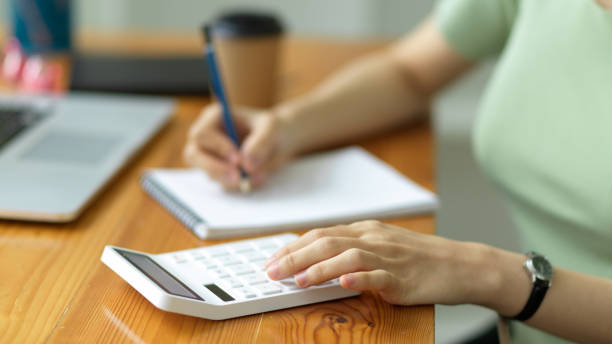 istock Female accountant calculating business project budgets and expenses by using calculator 1339188965