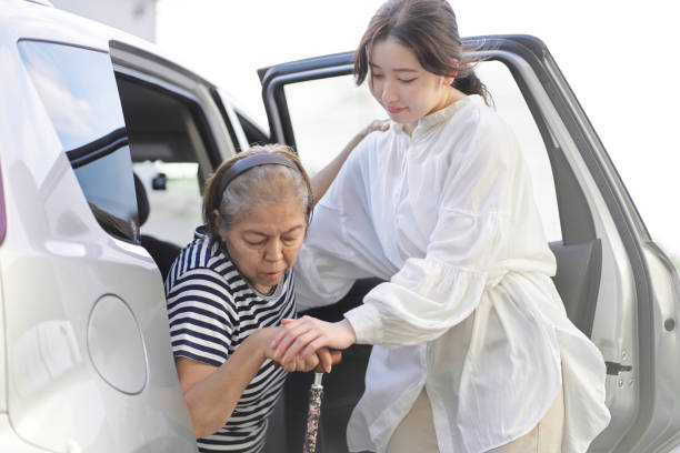 a woman who removes an elderly person from a car - driving car drive women imagens e fotografias de stock
