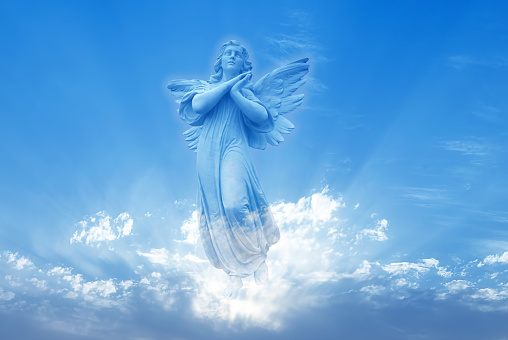 Escultura de ángel sobre fondo de cielo azul photo