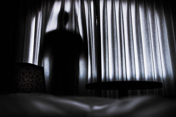 istock Silhouette of a man hinding behind a curtain 1339193938