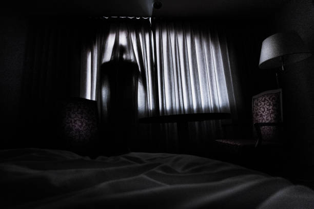 istock Silhouette of a man hinding behind a curtain 1339193948