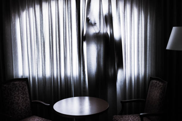 istock Silhouette of a man hiding behind a curtain 1339193957