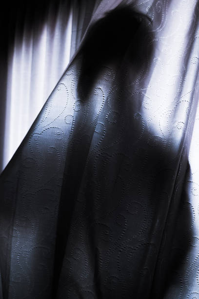 istock Silhouette of a man hiding behind a curtain 1339193966