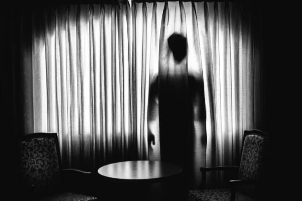 istock Silhouette of a man hiding behind a curtain 1339193980