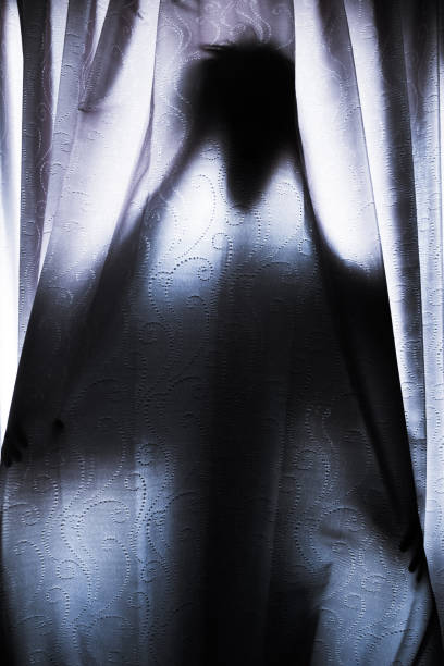 istock Silhouette of a man hiding behind a curtain 1339193981