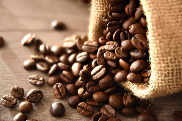 istock Sack full of fallen coffee beans on wooden table elevated 1339194906