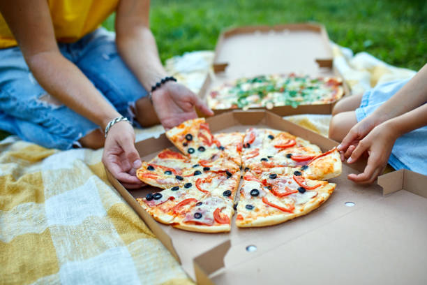 istock Sharing pizza, hands taking a piece of pizza from a box outdoor, 1339194989