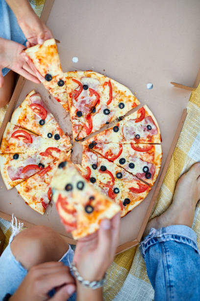 istock Sharing pizza, hands taking a piece of pizza from a box outdoor, 1339194991