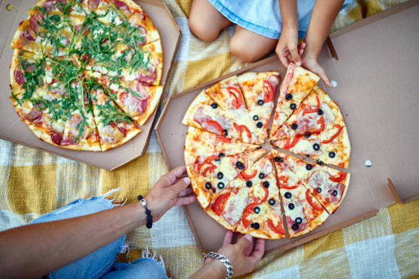 istock Sharing pizza, hands taking a piece of pizza from a box outdoor, 1339194993