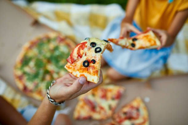 istock Sharing pizza, hands taking a piece of pizza from a box outdoor, 1339194996
