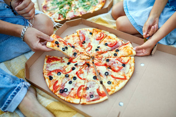 istock Sharing pizza, hands taking a piece of pizza from a box outdoor, 1339194997